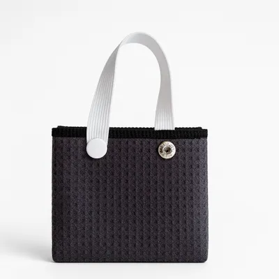 A close-up of an orange towel with a grey hanging loop and button closure, likely a feature of custom beach towels or personalized hand towels.